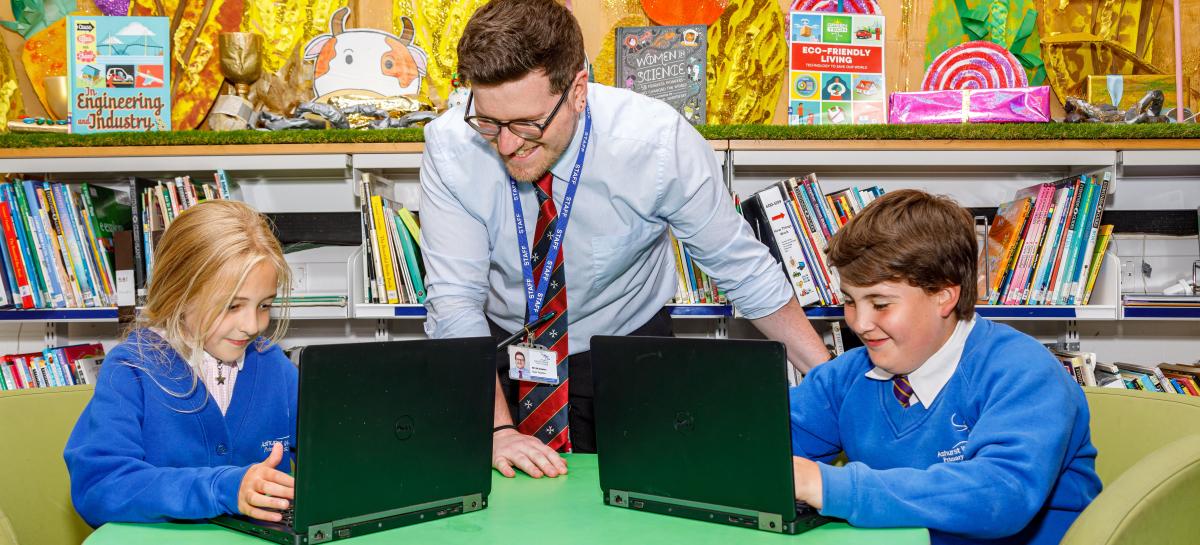A teacher and student using a laptop.