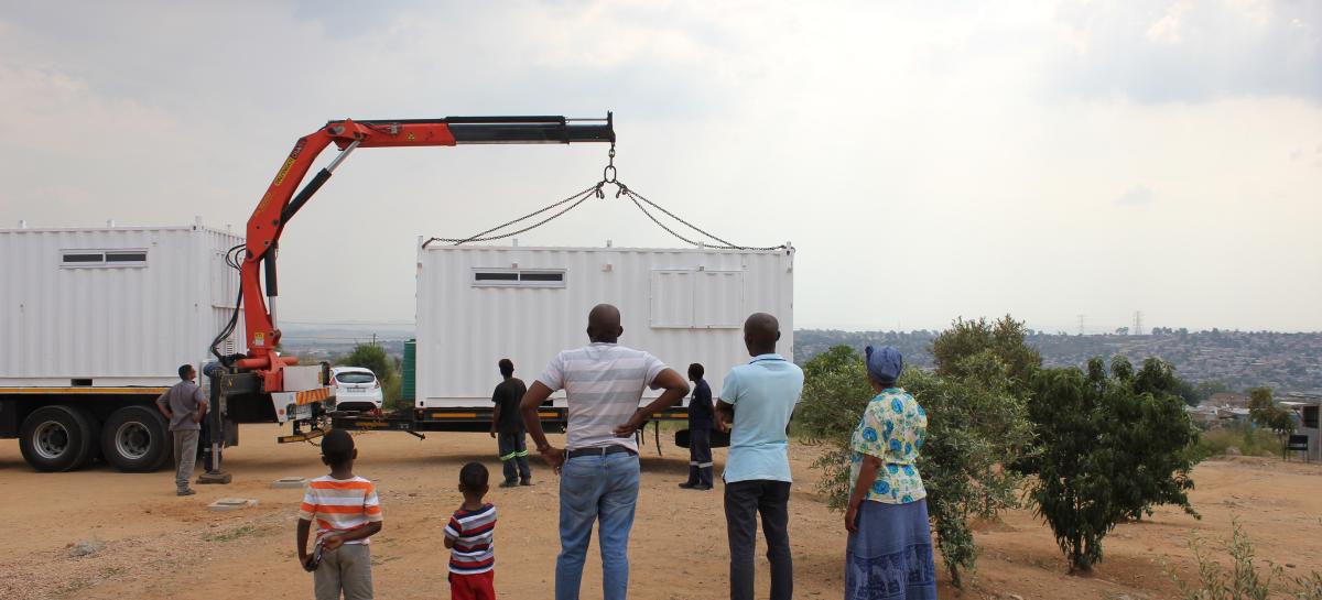 A group stands outside a Solar Learning Lab which is being placed