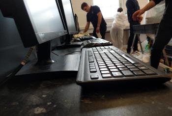 A computer keyboard with people working in the background