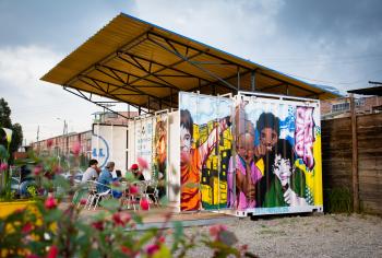 A group of people sit outside a converted shipping container