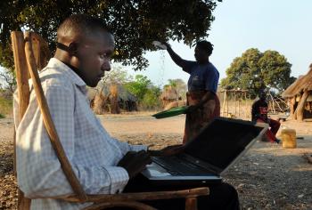 A man sits on a laptop near his field