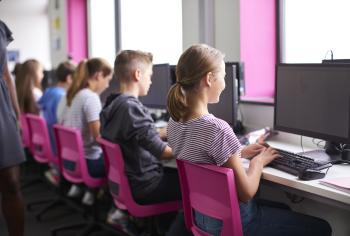 Children working on desktops in school.