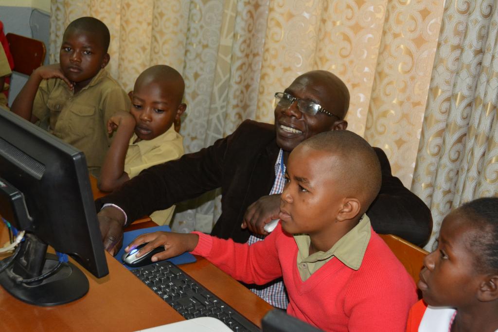 A teacher helping students at computers in Zimbabwe