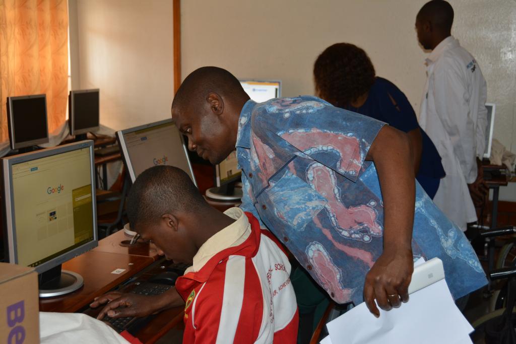 A teacher helps a student on a computer